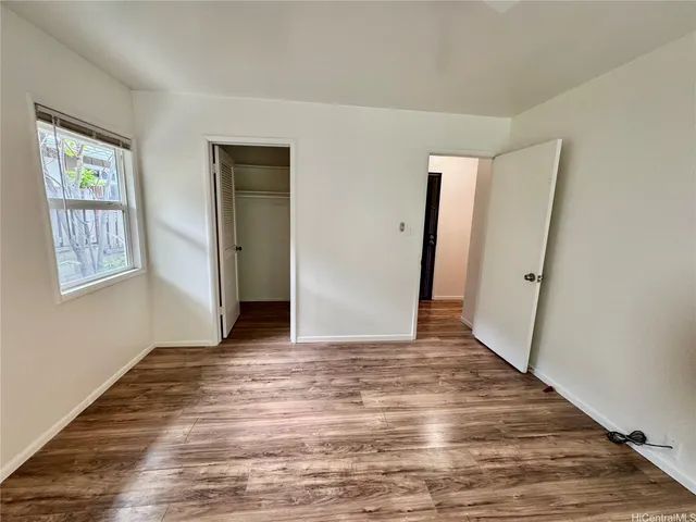a view of an empty room with wooden floor and window