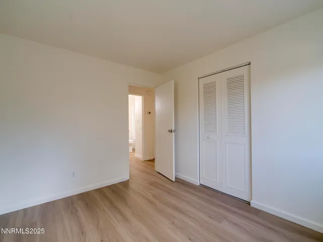 a view of an empty room with wooden floor and closet