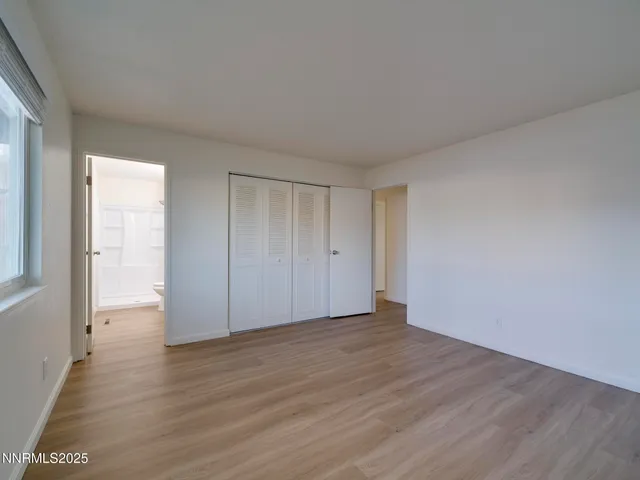 a view of an empty room with wooden floor and closet