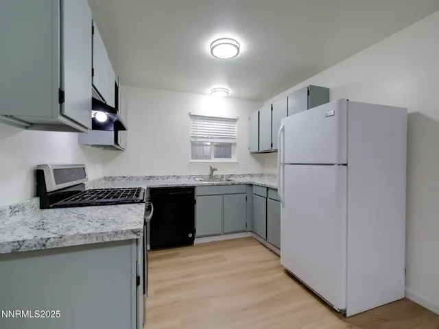 a kitchen with granite countertop a refrigerator stove top oven and sink