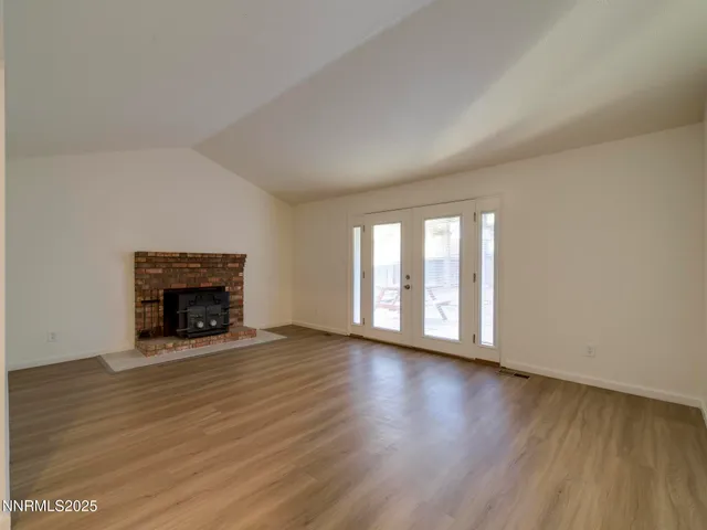 an empty room with wooden floor fireplace and windows