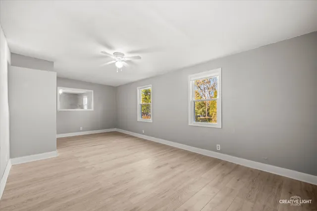 an empty room with windows and ceiling fan