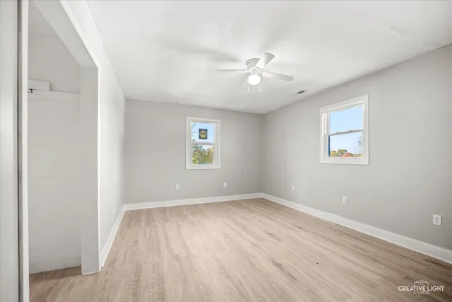 a view of empty room with wooden floor and fan