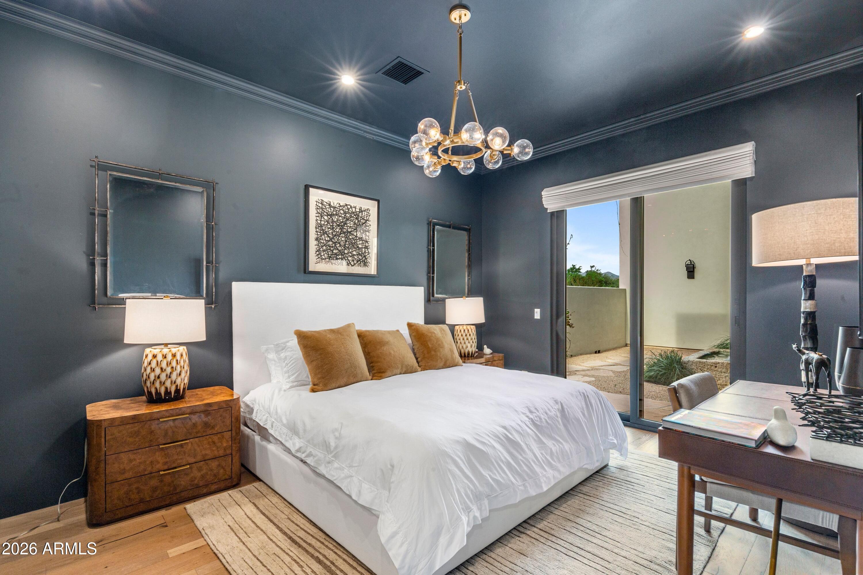 8307 East Gary Road Scottsdale, AZ 85260 - Photo 21 of 34 a bedroom with a large bed and a chandelier