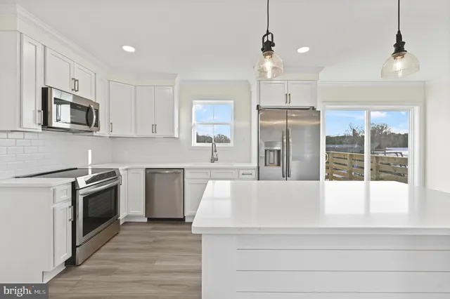 a large kitchen with cabinets wooden floor and stainless steel appliances