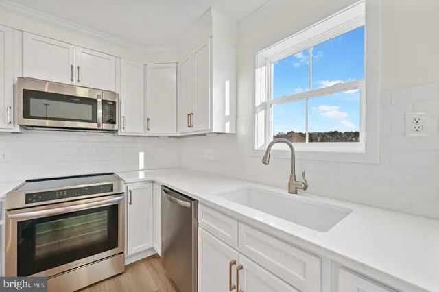 a kitchen with stainless steel appliances a stove microwave and sink