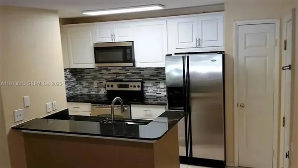 a kitchen with kitchen island a sink and a refrigerator