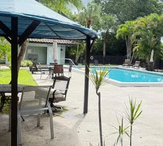 a view of a swimming pool with chairs and table in the patio