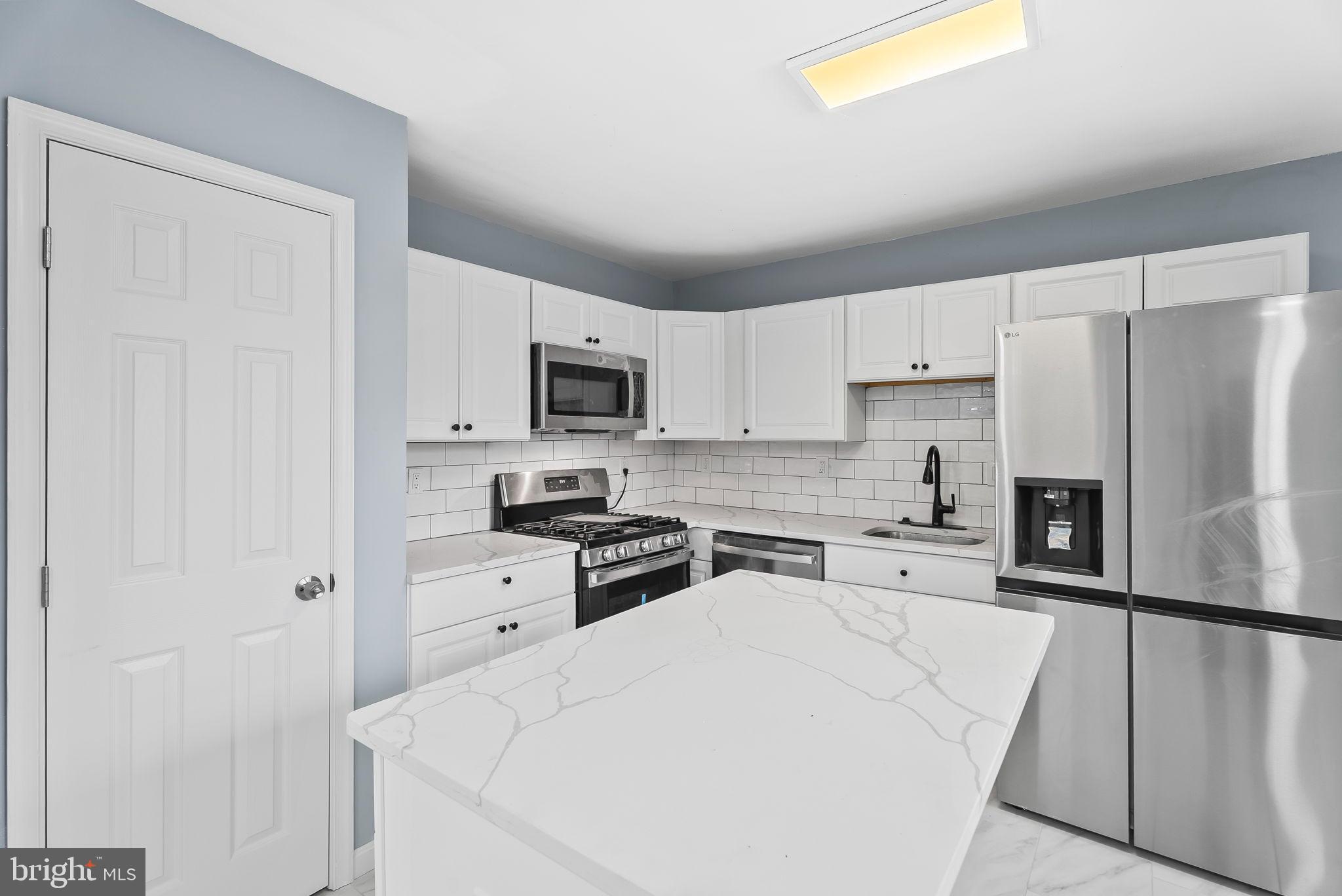 4302 Henderson Road Temple Hills, MD 20748 - Photo 11 of 33 a kitchen with white cabinets and stainless steel appliances