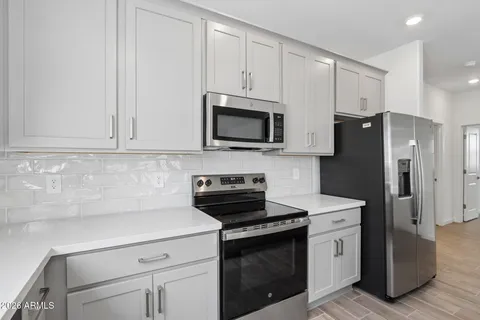 a kitchen with stainless steel appliances granite countertop white cabinets a stove a microwave and a refrigerator