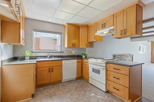 a kitchen with granite countertop cabinets stainless steel appliances a sink and a window