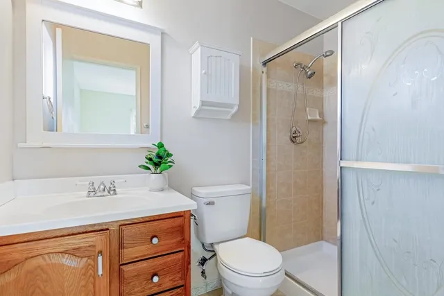 a bathroom with a granite countertop sink a toilet a shower and a mirror
