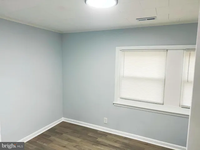 an empty room with wooden floor closet and windows