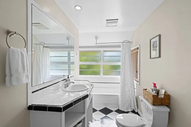 a bathroom with a granite countertop sink a toilet and a mirror