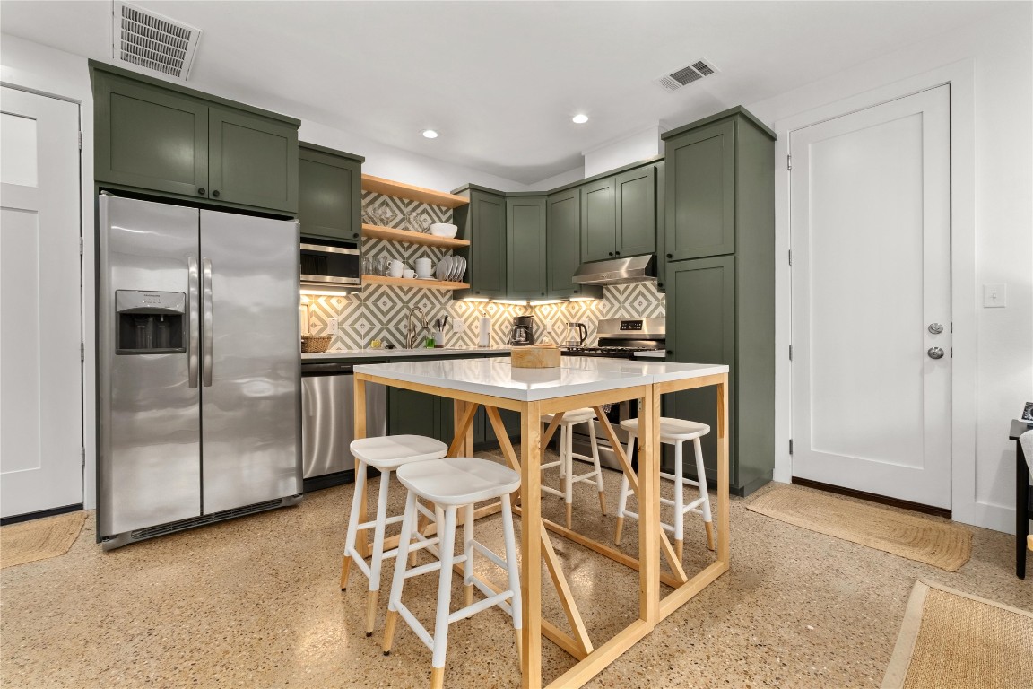 1806 Garden Street, Unit B Austin, TX 78702 - Photo 6 of 24 a kitchen with stainless steel appliances kitchen island granite countertop a refrigerator and microwave