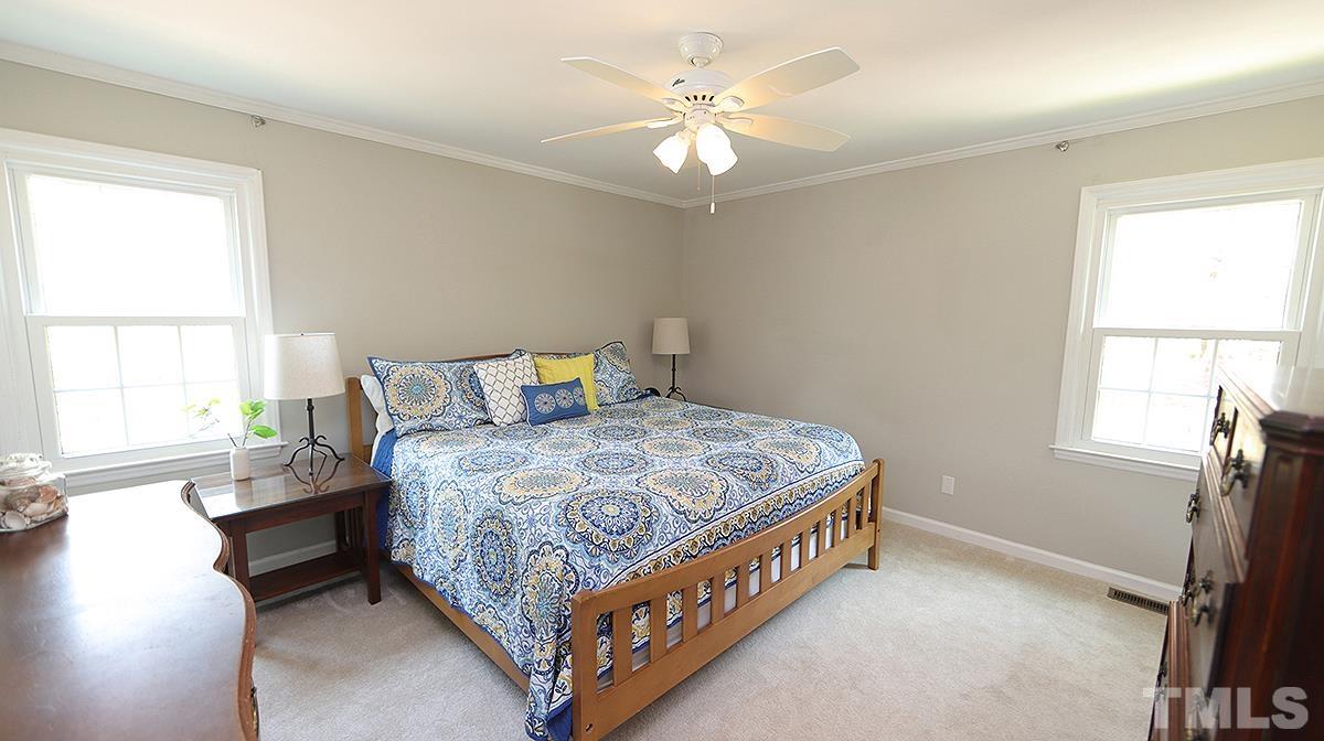 2504 Sawmill Road Raleigh, NC 27613 - Photo 8 of 13 a bedroom with a bed and a large window with wooden floor