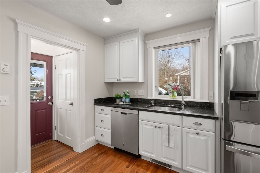 89 Coolidge Road Arlington, MA 02476 - Photo 10 of 22 a kitchen with stainless steel appliances granite countertop a sink a window and wooden cabinets