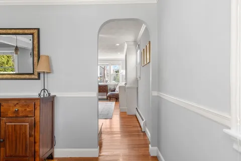 a view of a hallway with wooden floor and a bathroom