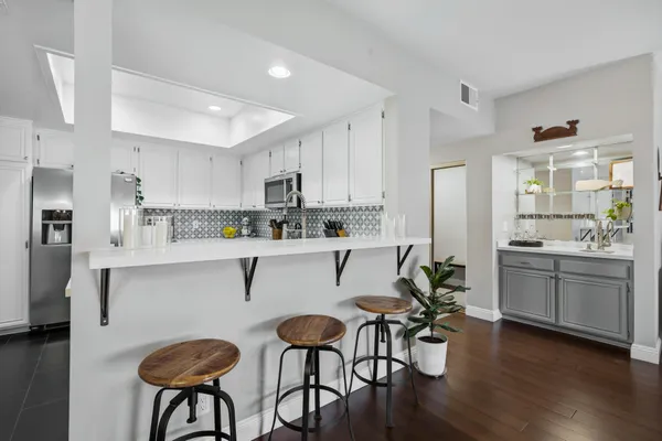 a kitchen with stainless steel appliances a table chairs refrigerator and sink