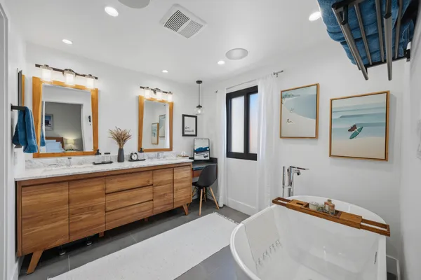 a spacious bathroom with a double vanity sink a mirror and a bathtub