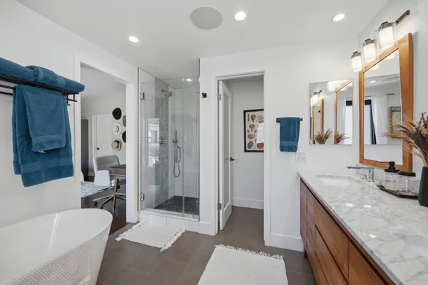 a spacious bathroom with a granite countertop tub sink a mirror a shower and vanity