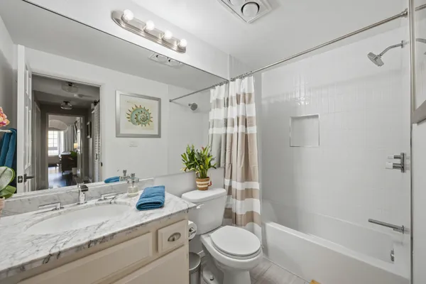 a bathroom with a granite countertop sink toilet a large mirror a shower and a bathtub
