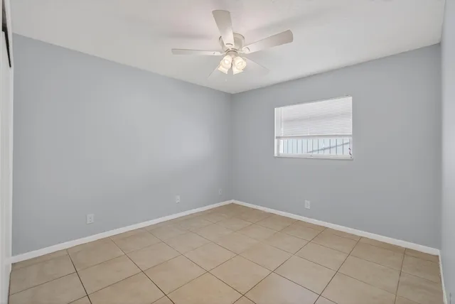 an empty room with a chandelier fan and windows