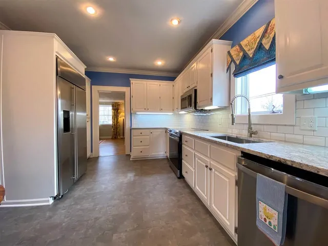 a kitchen with stainless steel appliances granite countertop a sink a stove and a refrigerator