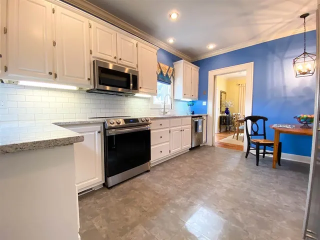 a kitchen with stainless steel appliances granite countertop a stove top oven a sink dishwasher a dining table and chairs with wooden floor