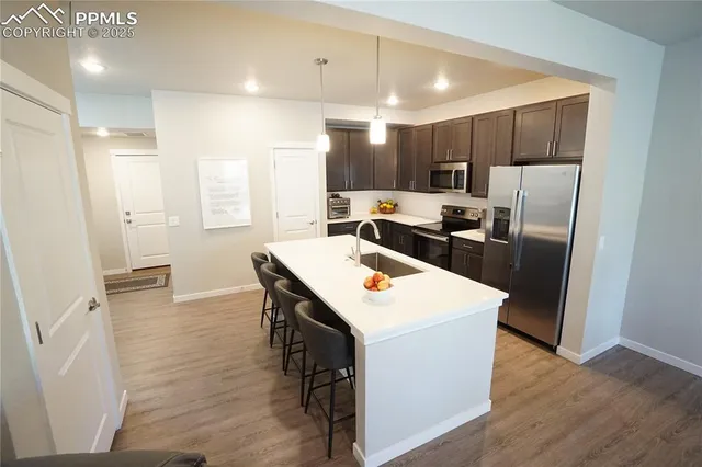 a kitchen with stainless steel appliances a refrigerator a sink dishwasher a stove with white cabinets and wooden floor