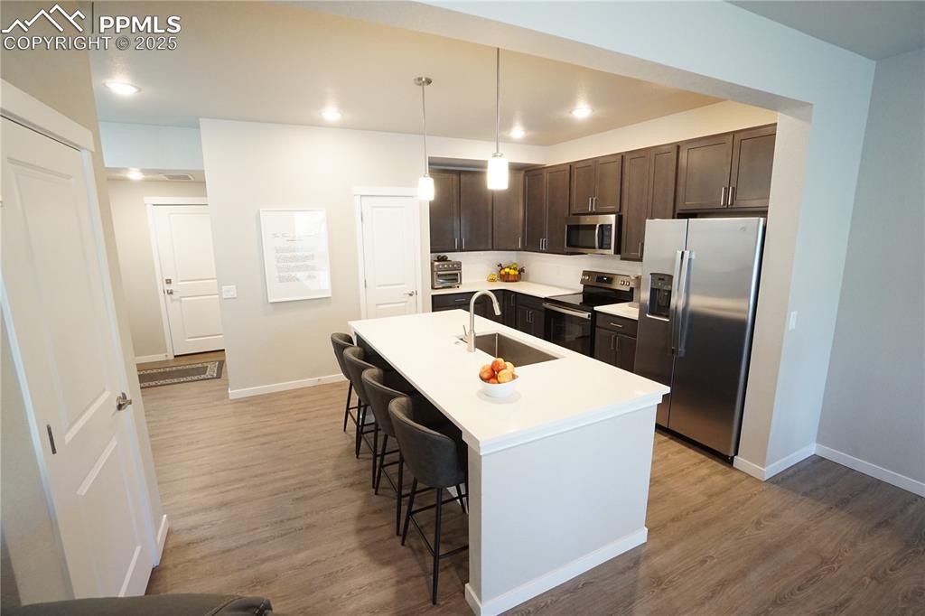 5309 Passport View Colorado Springs, CO 80922 - Photo 5 of 33 a kitchen with stainless steel appliances a refrigerator a sink dishwasher a stove with white cabinets and wooden floor