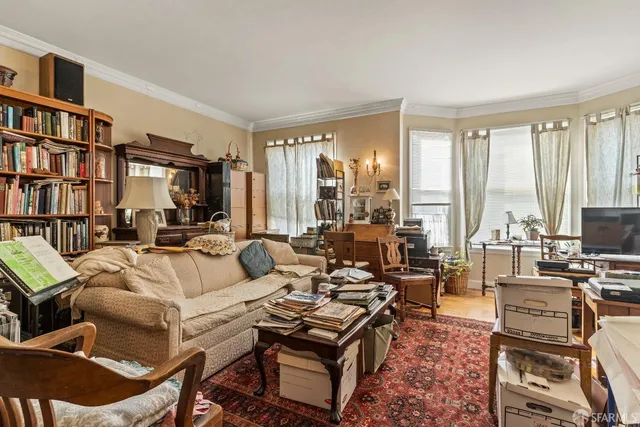 a living room with furniture a bookshelf and a large window