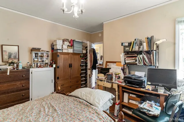 a bedroom with a bed and a computer on a desk next to a window