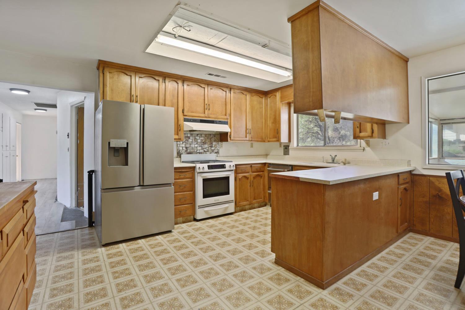 20200 Tuolumne Road North Tuolumne, CA 95379 - Photo 33 of 43 a kitchen with stainless steel appliances granite countertop a refrigerator sink and wooden cabinets