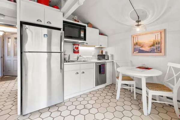 a kitchen with stainless steel appliances a white refrigerator stove a sink and chairs