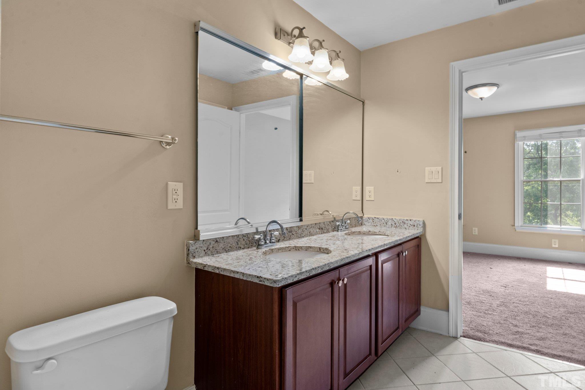 9501 Bluemont Court Raleigh, NC 27617 - Photo 76 of 85 a bathroom with a granite countertop sink a toilet and a mirror
