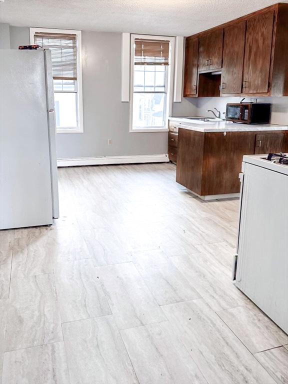 42 Mammoth Road Lowell, MA 01854 - Photo 8 of 15 a kitchen with stainless steel appliances granite countertop a stove a sink a refrigerator white cabinets and wooden floor