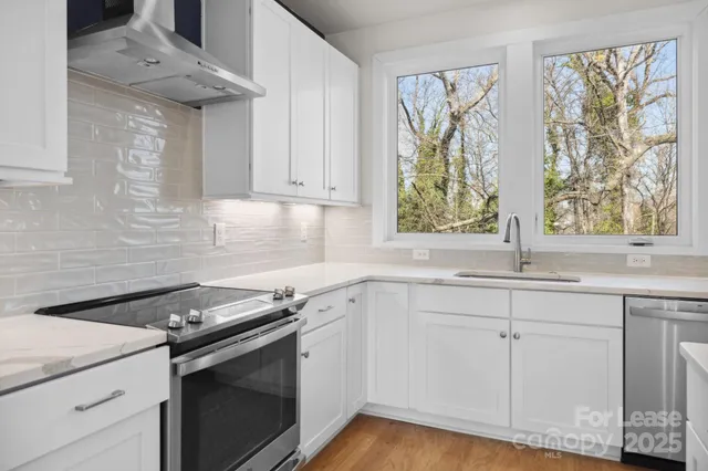 a kitchen with granite countertop white cabinets and a window
