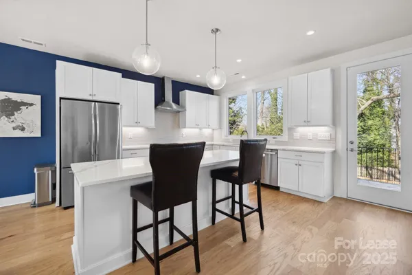 a kitchen with kitchen island a stove a refrigerator and a dining table with wooden floor