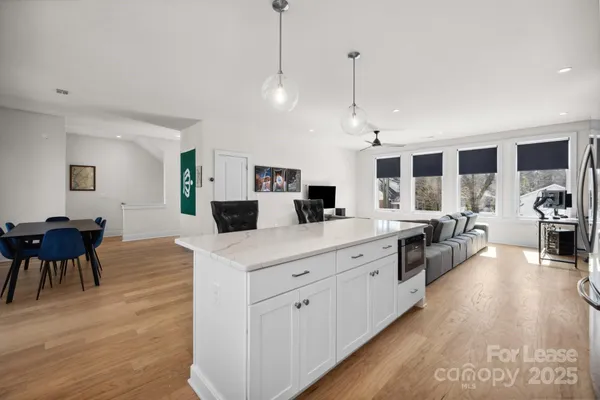 a large kitchen with stainless steel appliances kitchen island a large counter top a sink a stove and a wooden floors