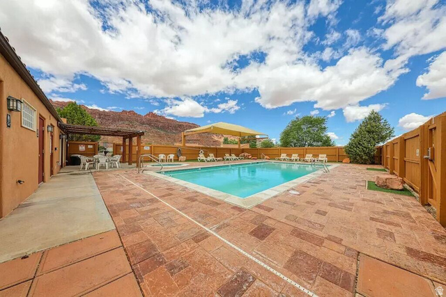 3853 South Red Valley Circle, Unit 22A1 Moab, UT 84532 - Photo 23 of 28 Community pool with a pergola, a patio, a fenced backyard, a mountain view, and outdoor dining area