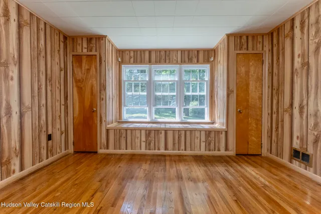 an empty room with wooden floor and windows with curtains