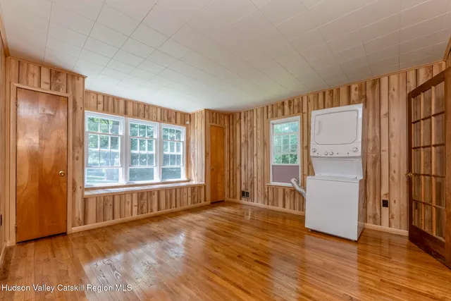 a view of an empty room with a window and wooden floor
