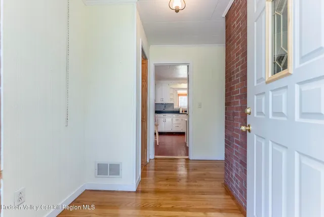 a view of a hallway with wooden floor and a bathroom