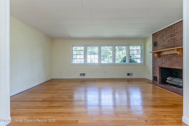 a view of empty room with wooden floor and fireplace
