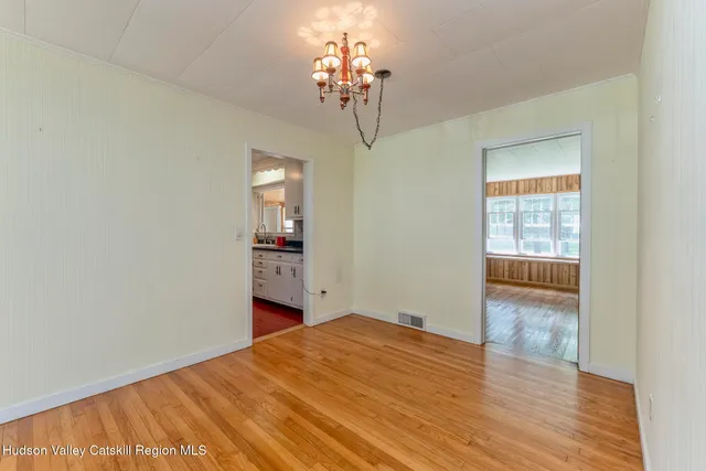 a big room with wooden floor chandelier and windows