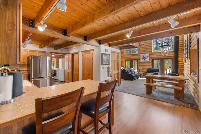 a dining hall with stainless steel appliances granite countertop a stove a refrigerator a dining table and chairs with wooden floor