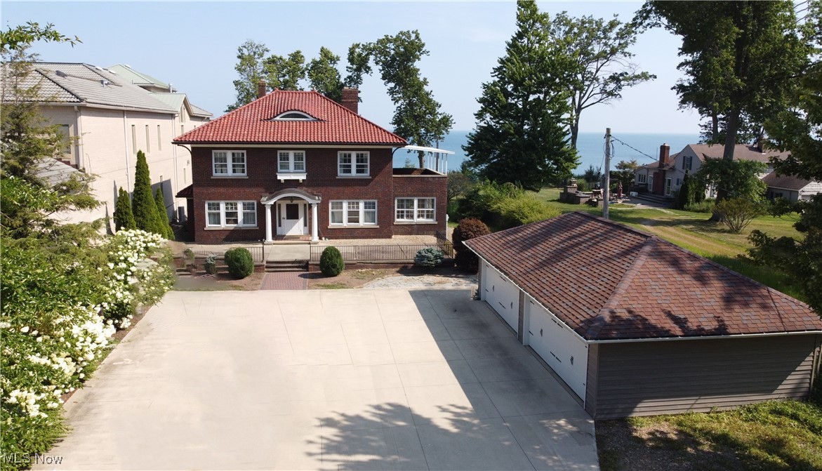 24510 Lake Road Bay Village, OH 44140 - Photo 2 of 45 View of front of property with a tiled roof, an outdoor structure, a garage, and a chimney