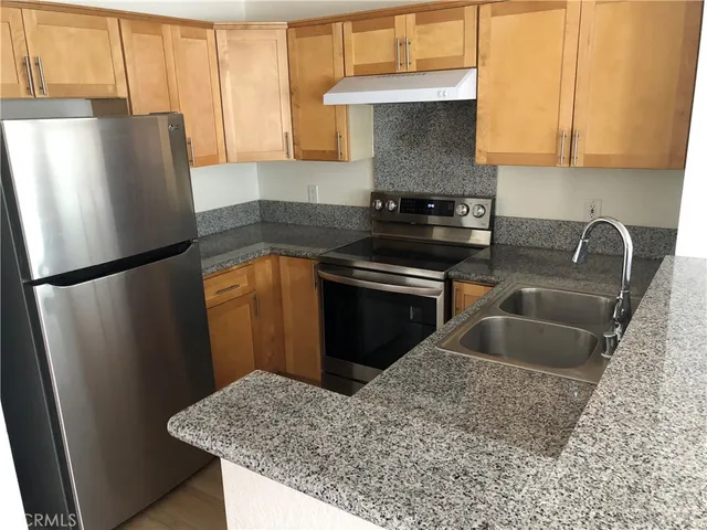 a kitchen with stainless steel appliances granite countertop a refrigerator a sink a stove and a window