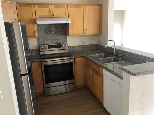 a kitchen with granite countertop a sink stove and refrigerator